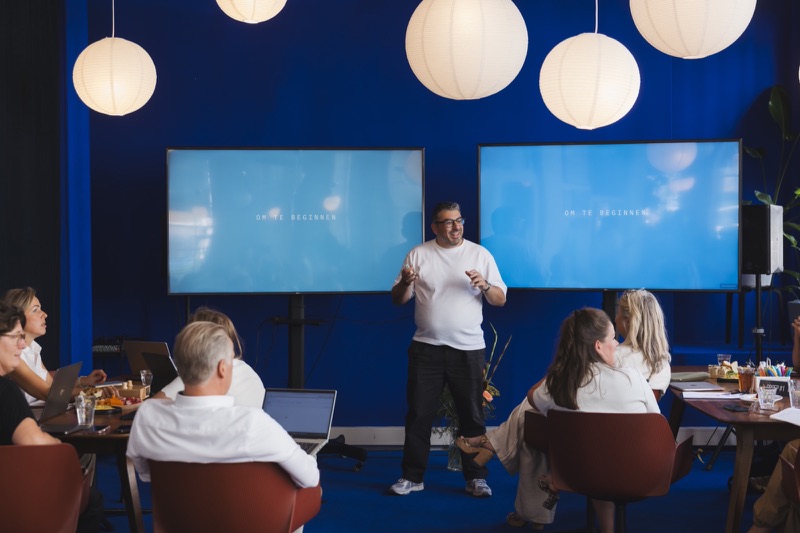 Serop Yildiz geeft een workshop voor een groep in een blauwe zaal